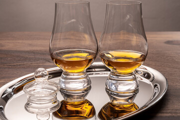 Tasting glasses of single malt scotch whisky served on steel mirror tray with reflection