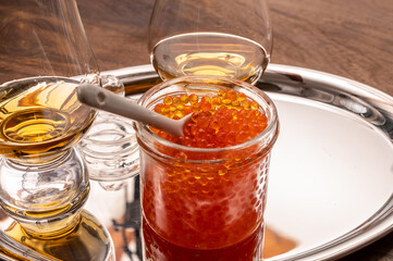 Pairing of single malt scotch or japanese whisky and salted red trout fish caviar in glass jar