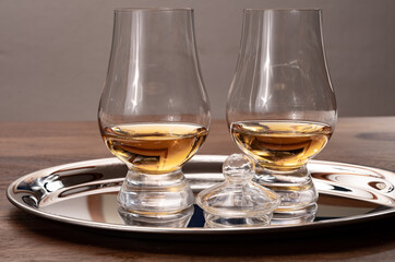 Tasting glasses of single malt scotch whisky served on steel mirror tray with reflection
