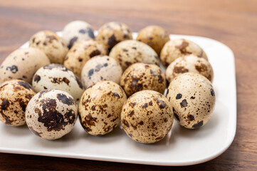 Fresh small spotted partridge eggs on white board