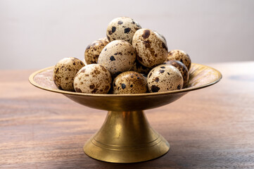 Fresh small spotted partridge eggs on bronze plate