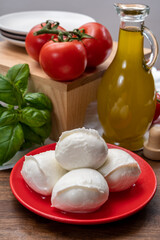 Cheese collection, small fresh white soft mozzarella cheese balls served with red tomatoes and fresh green basil from Italy