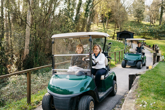 Women driving golf carts in park - Powered by Adobe