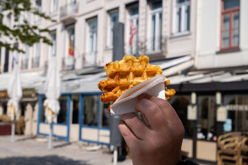 Eating of Belgian sugar waffles, street food in Bruges