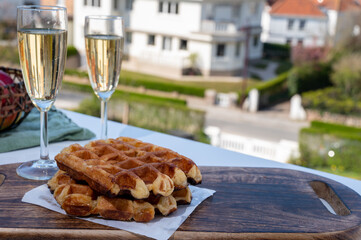Breakfast with fresh baked belgian waffles and brut champagne sparkling wine in flute glasses served on outdoor bistro terrace in France