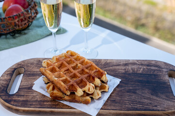 Breakfast with fresh baked belgian waffles and brut champagne sparkling wine in flute glasses served on outdoor bistro terrace in France