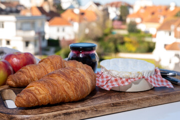 Obraz na płótnie Canvas French breakfast with fresh baked croissants and cheeses from Normandy, camembert and neufchatel served outdoor with nice city view