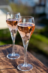 Drinking of rose champagne sparkling wine from flute glasses on outdoor terrace in France