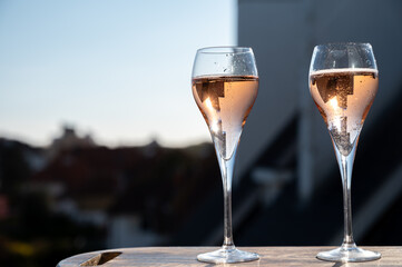 Drinking of rose champagne sparkling wine from flute glasses on outdoor terrace in France