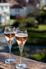 Drinking of rose champagne sparkling wine from flute glasses on outdoor terrace in France