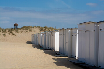 Fototapeta na wymiar White beach huts on yellow sandy beach in small Belgian town Knokke-Heist, luxury vacation destination, summer holidays