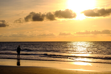 Fototapeta na wymiar Lady walking on beach at sunrise on Jekyl Island,GA