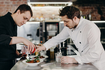Chefs dressing dish in restaurant kitchen