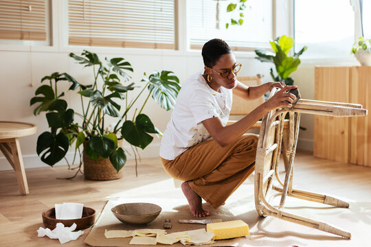 Black female artisan restoring bamboo table in studio