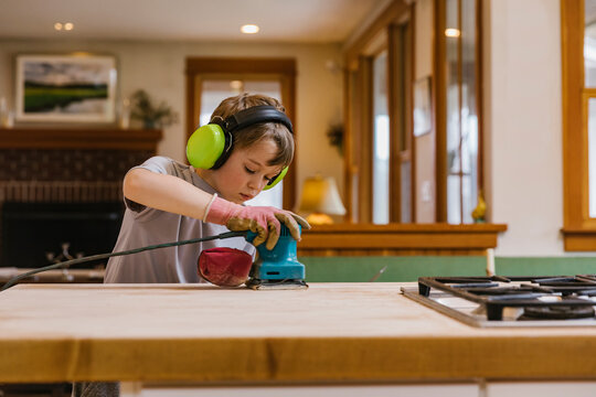 Young Woodworker using Sander on kitchen Island 