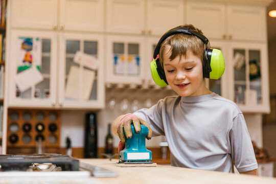 Happy Young Woodworker using Sander with Ear Protection 