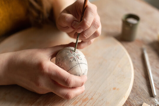 Woman's hands painting clay egg 