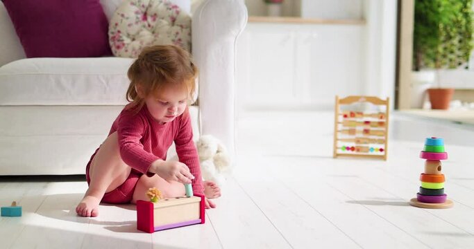 cheerful toddler baby girl playing wooden toys at home, sunny summer day