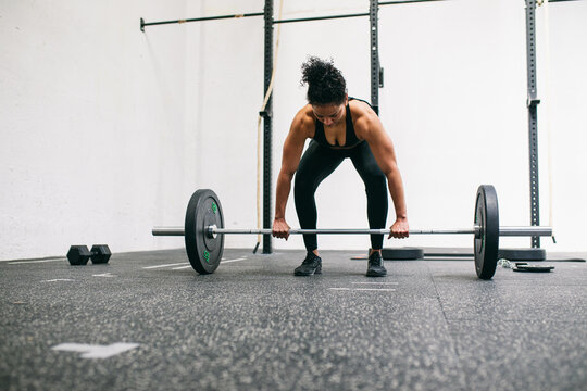 Strong Hispanic weightlifter deadlifting barbell 