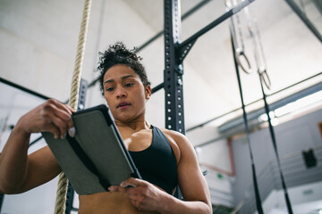  Hispanic sportswoman with tablet in gym