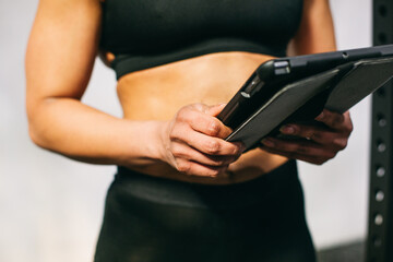 Crop sportswoman using tablet in gym 