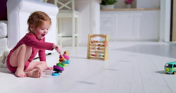 cheerful toddler baby girl playing wooden toys at home, sunny summer day