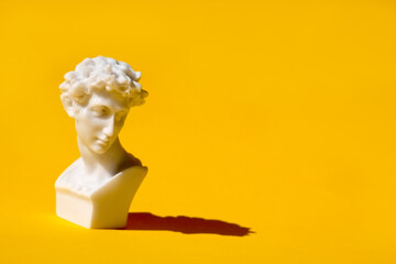 white statue head on yellow background. Ancient greek head sculpture. . High quality photo - obrazy, fototapety, plakaty
