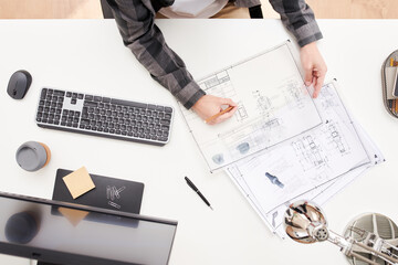 Modern engineer drawing blueprint at desk
