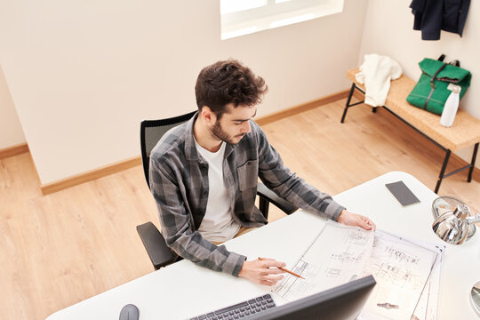 Serious architect with blueprint in office