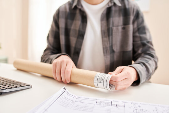 Crop man taking blueprint out of tube