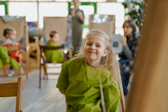 girl in uniform at a drawing class, drawing with paints at an easel