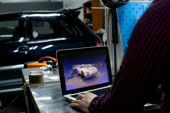 Crop view of man working with 3D model of car made by pointcloud inside of service station 