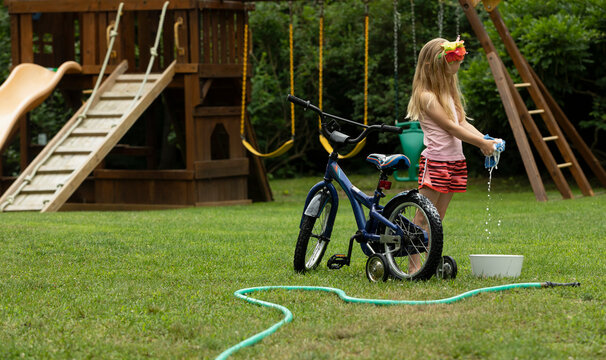 Young girl Washing her bicycle in the backyard of home 