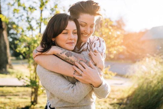Happy lesbian couple hugging outside in sunlight