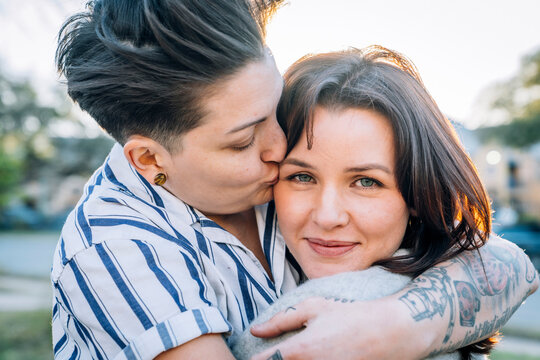 Lesbian woman hugging kissing wife on cheek