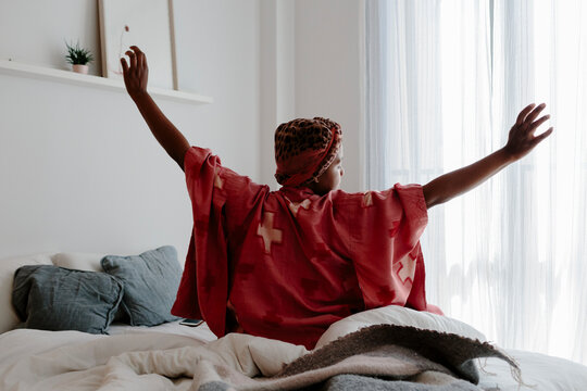 Woman stretching in bedroom as she wakes up