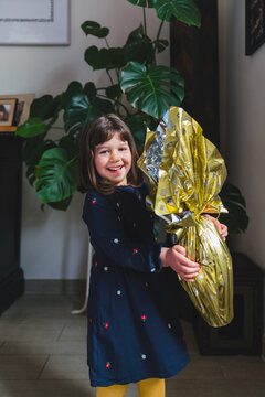 Happy Little Girl Holding a Wrapped Chocolate Easter Egg