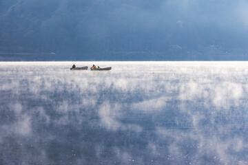 早朝の湖の釣人