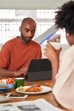 Black man using pad at breakfast.