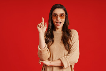 Beautiful young woman in casual clothing smiling and keeping index finger