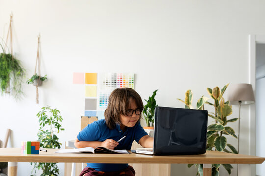 kid sitting on desk using laptop