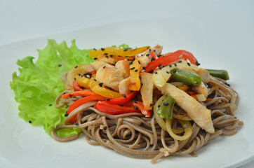 Plate of noodles with meat and vegetables isolated on white background