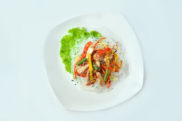 Plate of noodles with meat and vegetables isolated on white background, top view