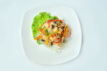 Plate of noodles with meat and vegetables isolated on white background, top view