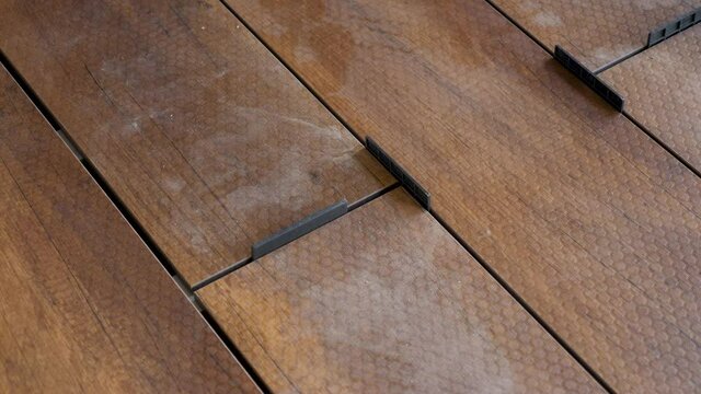 Carpenter sets spacing of deck boards on floor wood panel. Flooring installation work master builder construction home renovation building wood deck plank wooden floor covering. Repair home deck floor