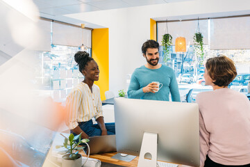 Multiracial coworkers working with gadgets in office