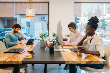Multiracial coworkers working with gadgets in office