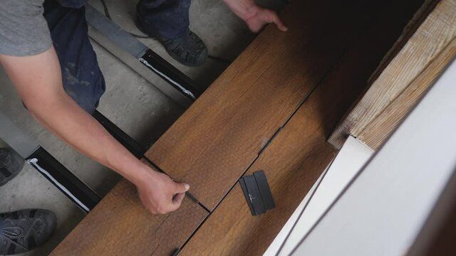 Carpenter sets spacing of deck boards on floor wood panel. Flooring installation work master builder construction home renovation building wood deck plank wooden floor covering. Repair home deck floor