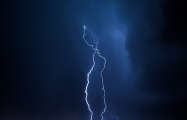 Lightning in the night sky. Thunderstorm over the city. Stormy clouds and rainy weather.