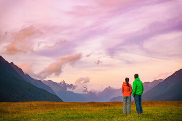 Obraz premium New Zealand hikers backpackers tramping on Routeburn Track, famous trail in the South Island of New Zealand. Couple looking at nature landscape. Fiordland and Mount Aspiring National Park, New Zealand